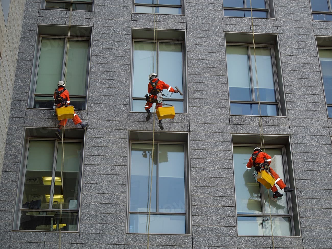 Reinigungsteam bei der Fassadenreinigung an einem Hochhaus in Seilsicherung